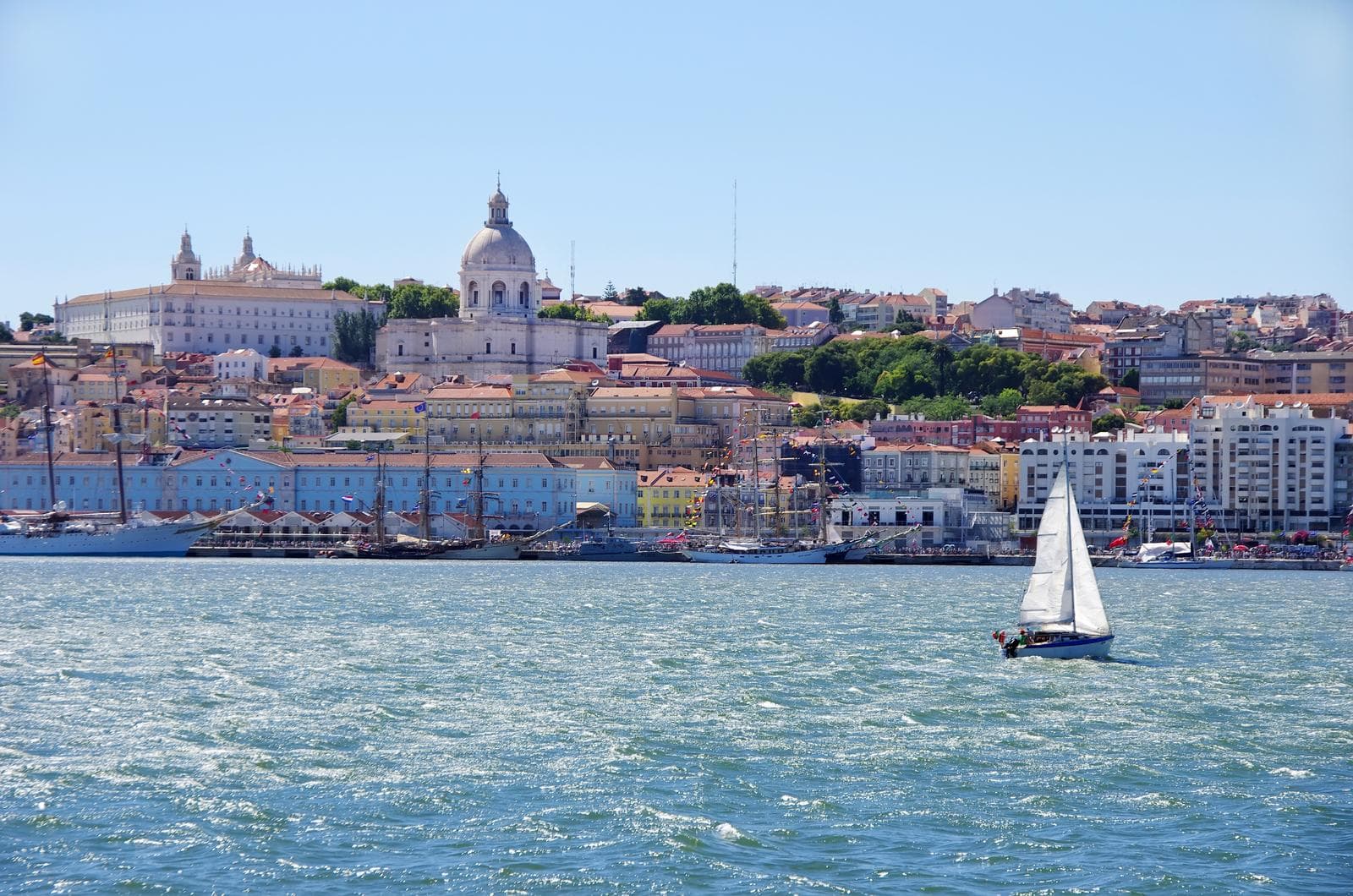 Segelboot vor farbenfroher Altstadt von Lissabon, Portugal; sonniger Himmel.