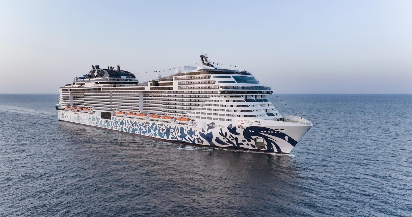 Modernes Kreuzfahrtschiff mit blau-weißem Design auf dem offenen Meer bei ruhiger See.