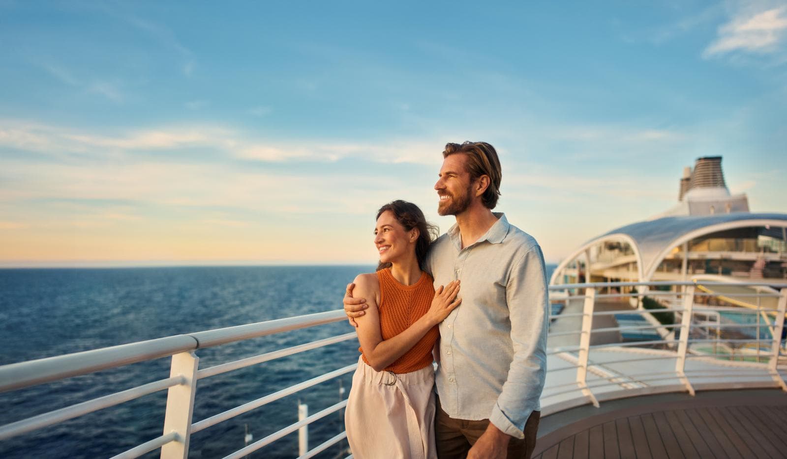 Pärchen steht an Deck und schaut auf das Meer hinaus.