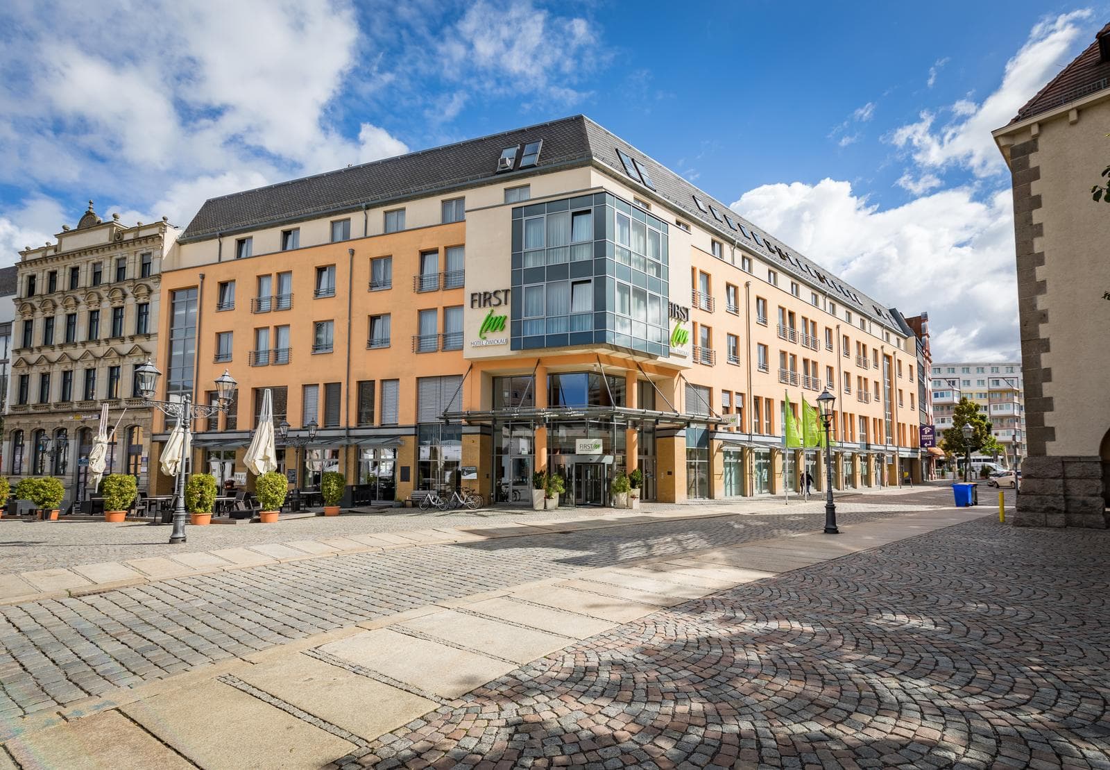 Modernes Hotel in Zwickau, Deutschland mit oranger Fassade und einladender Terrasse.