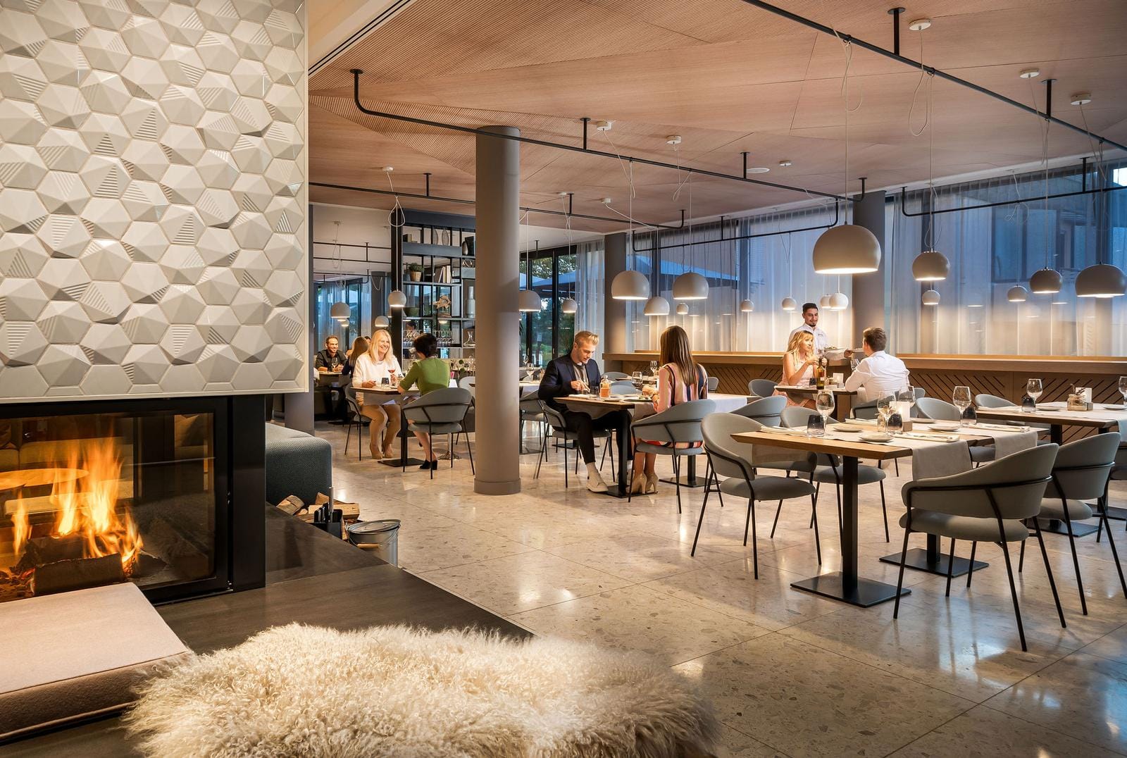 Modernes Hotelrestaurant mit Kamin, Holzakzenten und gemütlicher Atmosphäre.