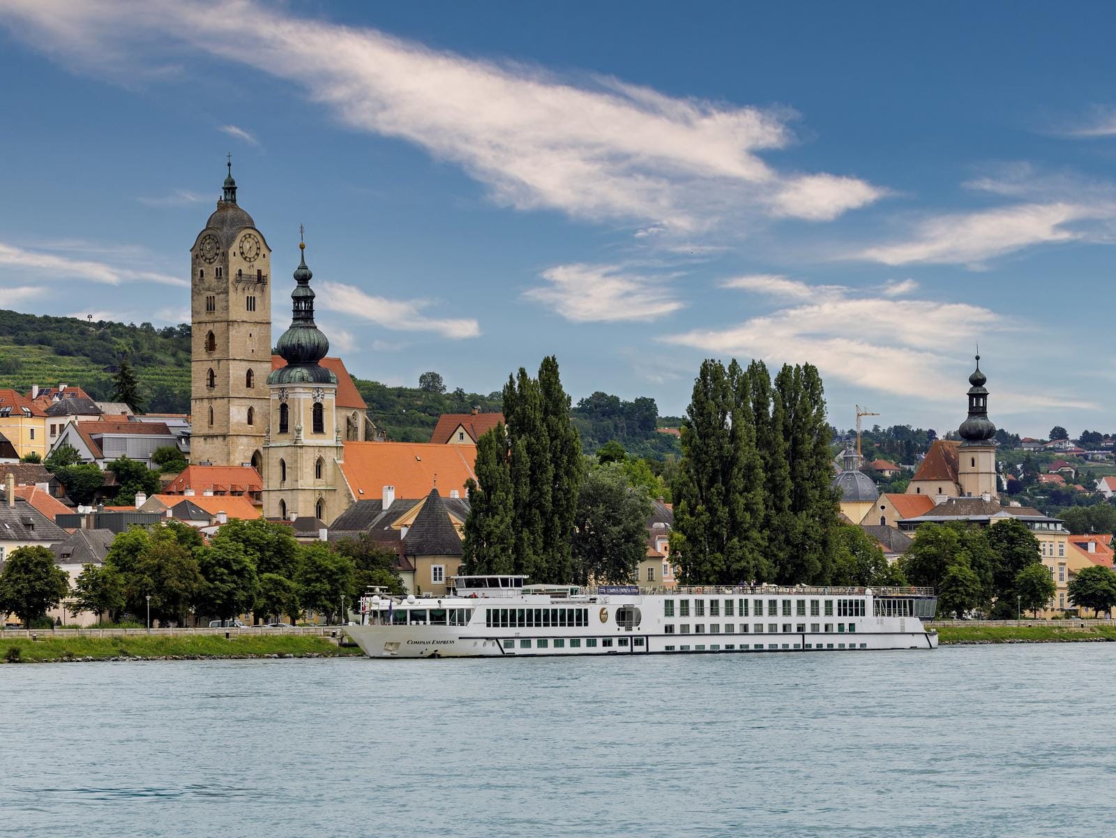 Idyllische Donausicht in Österreich, mit prächtiger Kirche und Flusskreuzfahrtschiff.