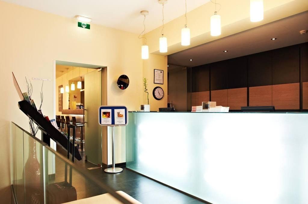Helle Lobby mit moderner Rezeption, schwarzen Akzenten und stilvoller Beleuchtung.