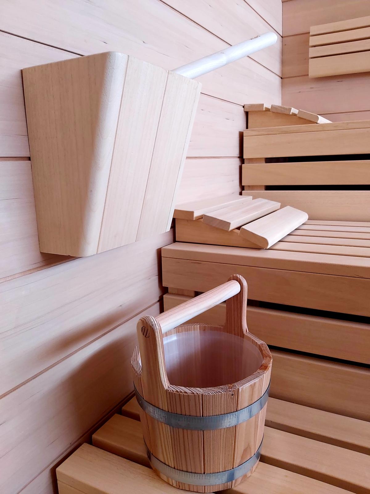 Holzsauna mit Eimer und Schöpfkelle; moderne, minimalistische Atmosphäre.