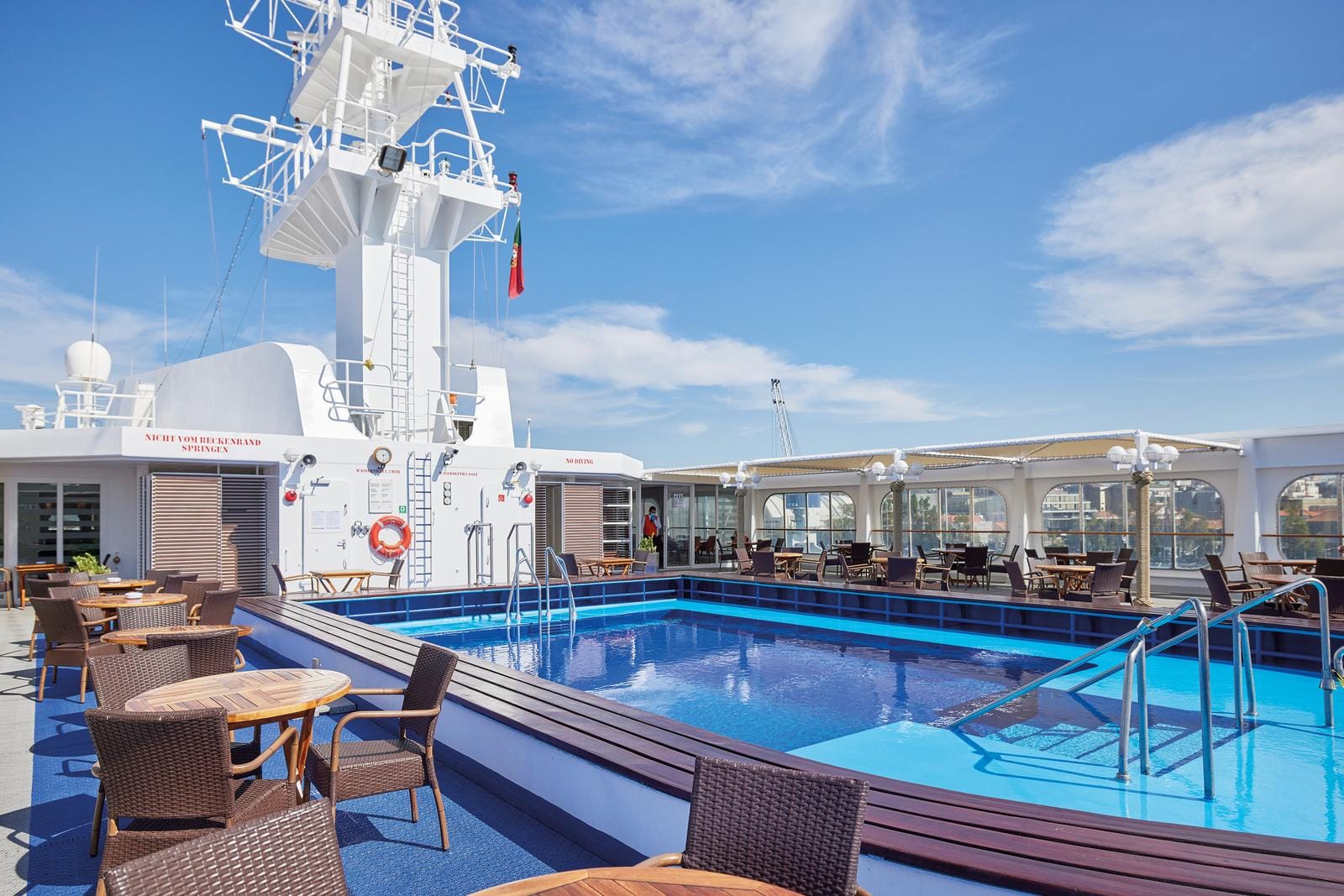 Ein Kreuzfahrtschiff-Pooldeck mit blauem Himmel, möglicherweise in einem europäischen Hafen.