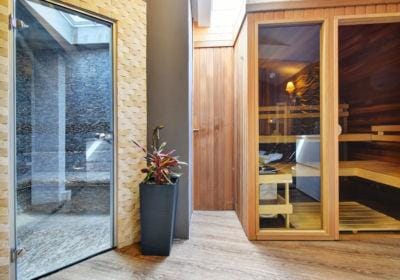 Moderne Hotel-Sauna mit holzverkleidetem Innenraum, Steinwänden und Pflanzendekor.