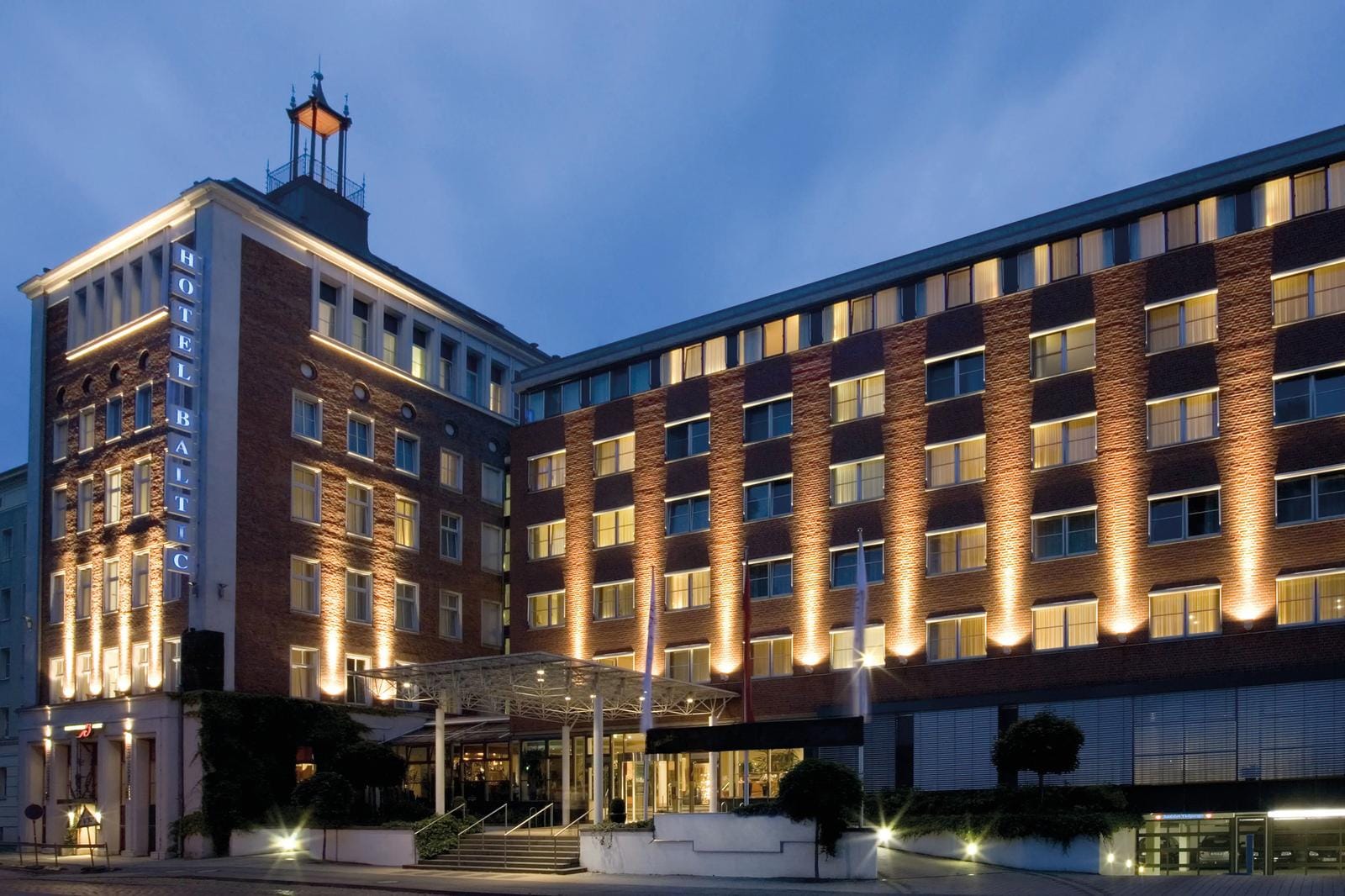Außenansicht eines Backsteinhotels mit stimmungsvoller Beleuchtung in der Abenddämmerung.