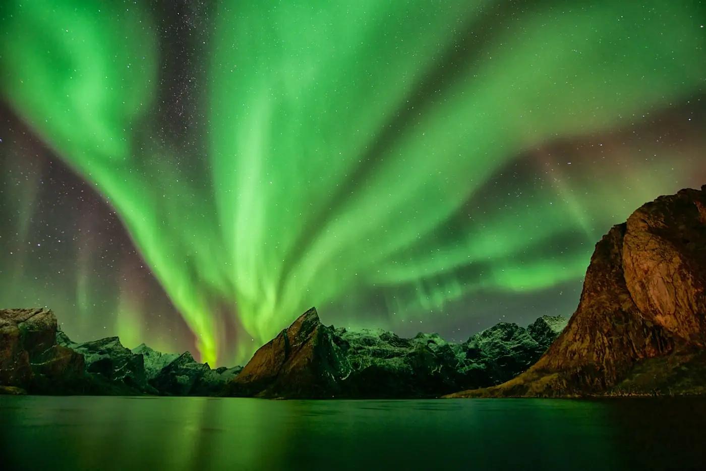 Nordlichter über norwegischen Fjorden mit grünen, leuchtenden Himmelsbändern.