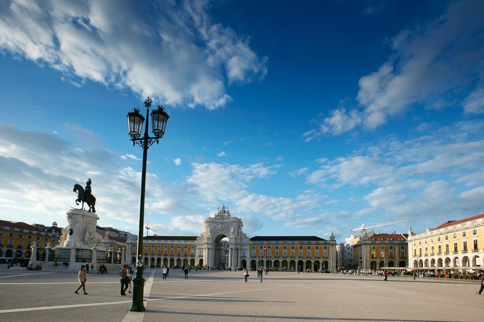 Weitläufiger Platz in Lissabon, Portugal mit Reiterstatue und Triumphbogen, blauer Himmel.