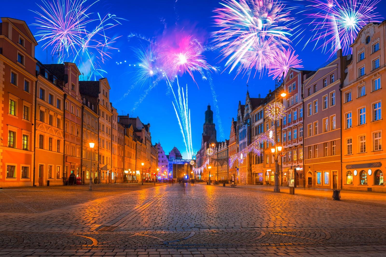 Bunte Feuerwerke über erleuchtetem Platz mit historischen Häusern in Breslau, Polen.