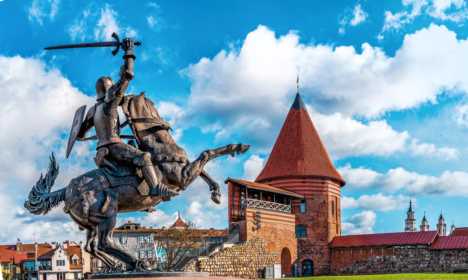 Ritterstatue vor Kaunas Burg, Litauen, bei blauem Himmel und Wolken.