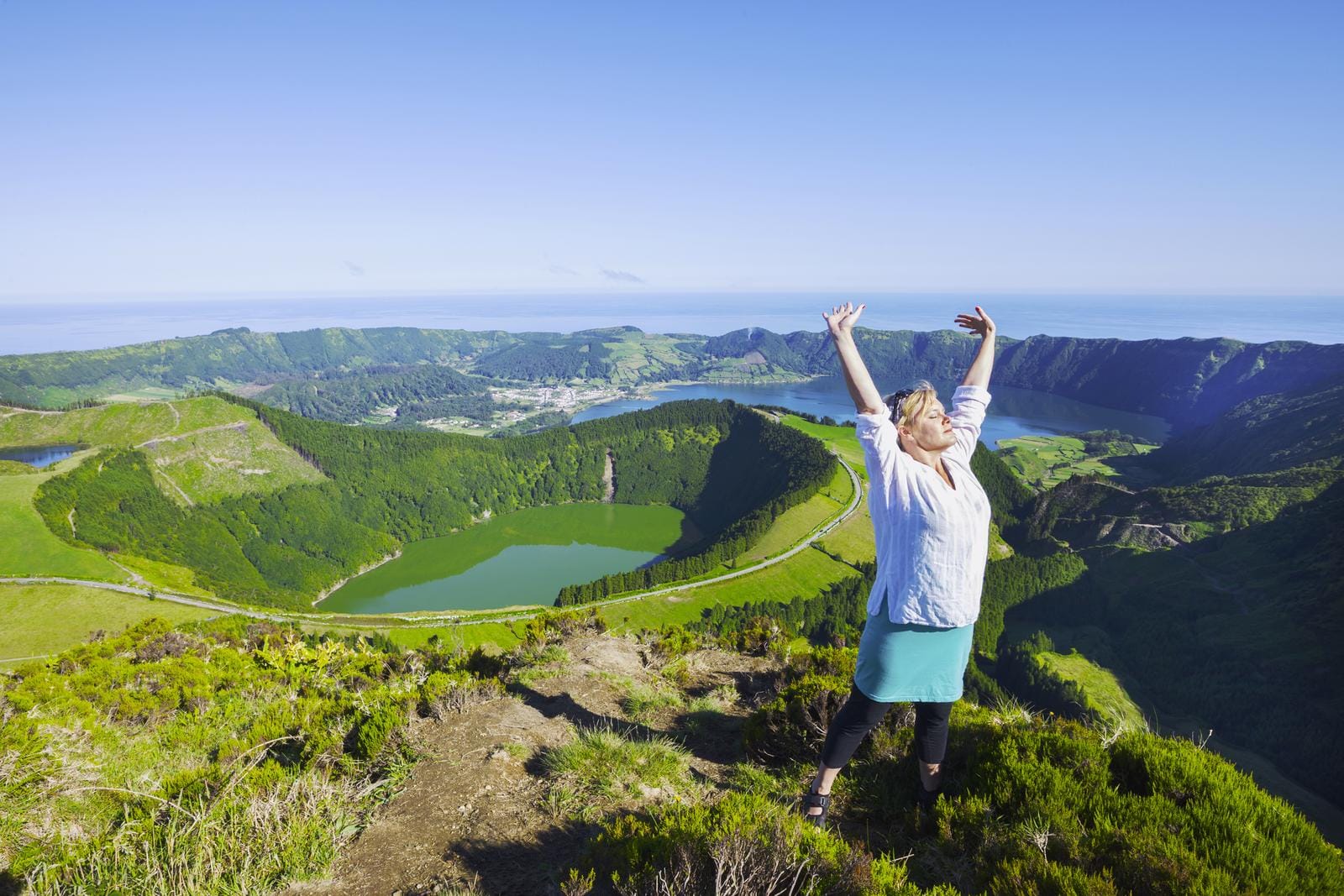 Frau genießt Aussicht auf grüne Kraterlandschaft und Seen in São Miguel, Azoren.