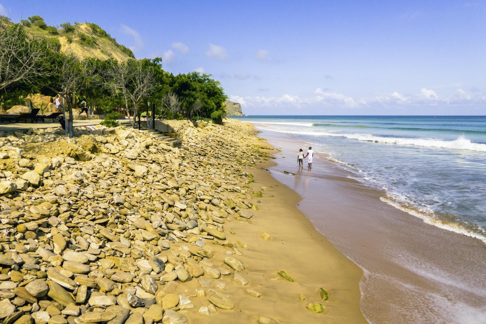 Ein idyllischer Küstenabschnitt mit Sandstrand und sanften Wellen lädt in Angola zum entspannten Strandspaziergang ein.