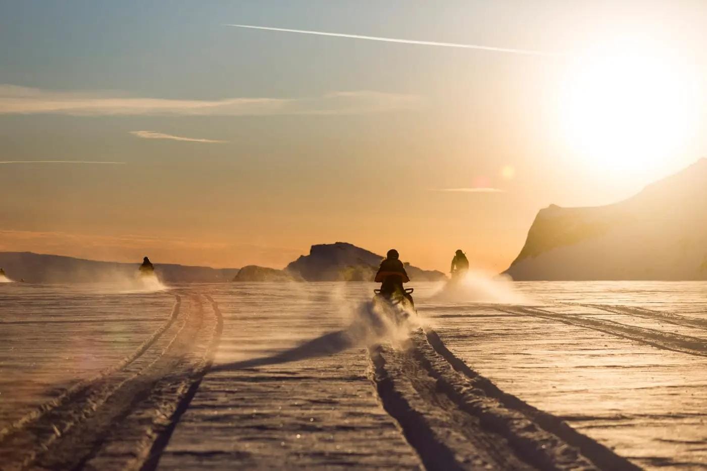 Motorschlitten auf schneebedeckter Landschaft bei Sonnenuntergang, Island.