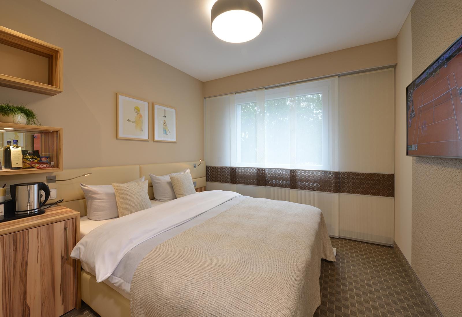 Modernes Hotelzimmer mit Doppelbett, hellem Holz, Wandkunst und Flachbildfernseher.