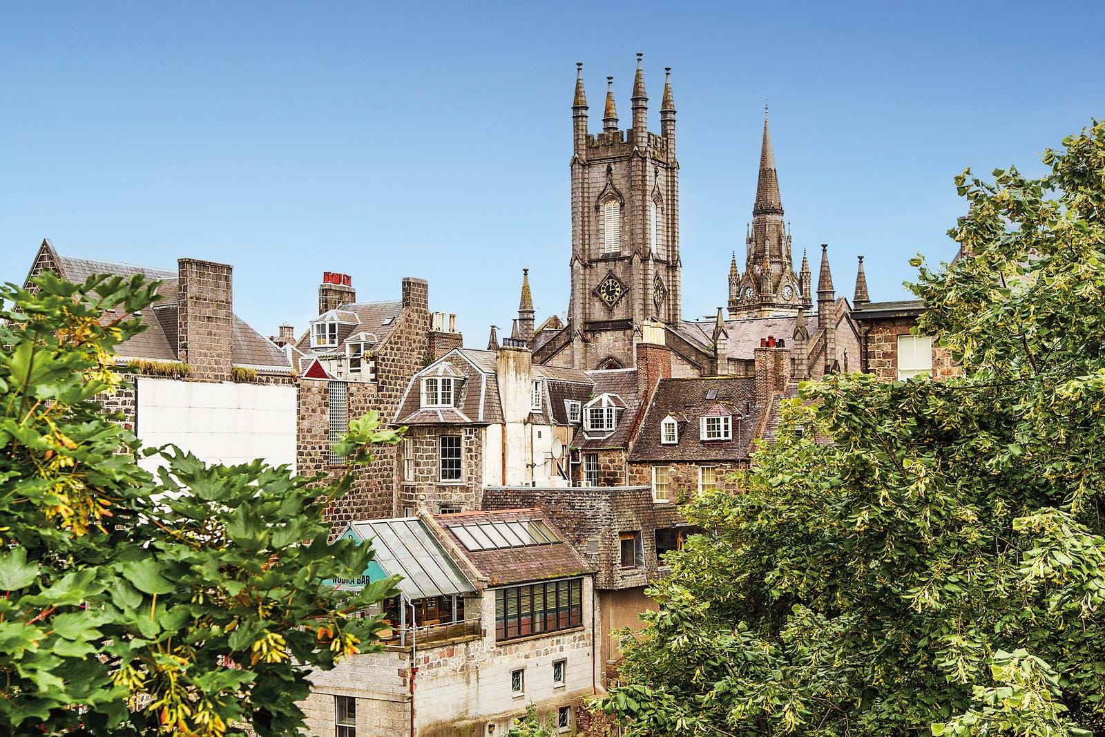 Historische Altstadt mit gotischen Türmen und Fachwerkhäusern unter blauem Himmel.