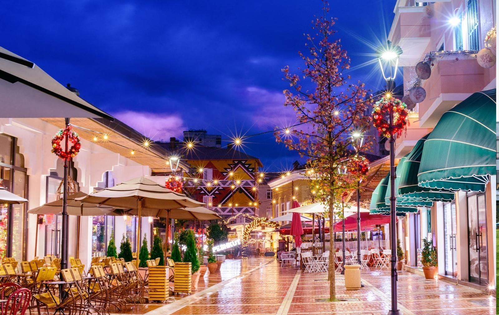 Beleuchtete Stadtgasse bei Nacht, festlich dekoriert mit bunten Lichtern und Girlanden.