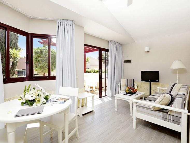 Helles Hotelzimmer mit moderner Einrichtung, weiß-blauen Möbeln und Terrassenzugang.