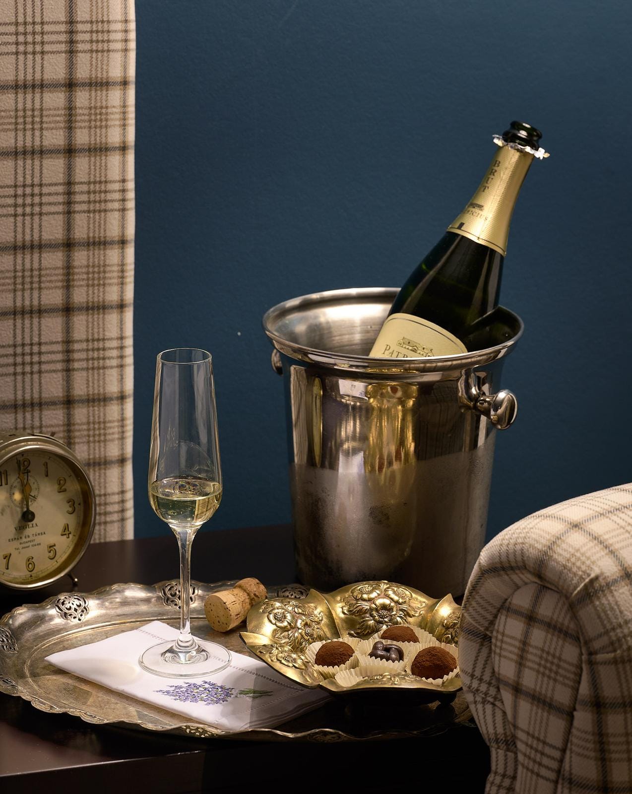 Champagner und Pralinen auf Tablett in stilvoller Zimmerdekoration mit antiker Uhr.