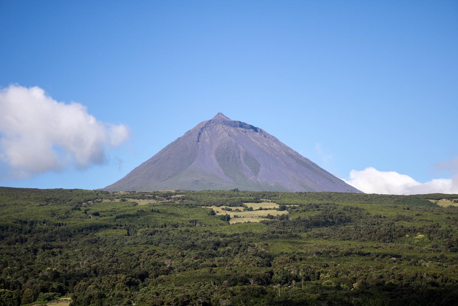 Vulkan Pico auf den Azoren unter klarem Himmel, umgeben von grüner Landschaft.