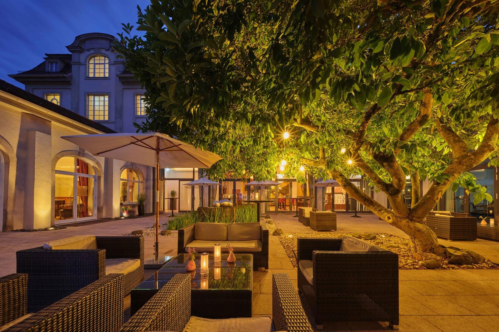 Stimmungsvolle Hotelterrasse bei Nacht mit Sitzgelegenheiten und stimmungsvoller Beleuchtung.