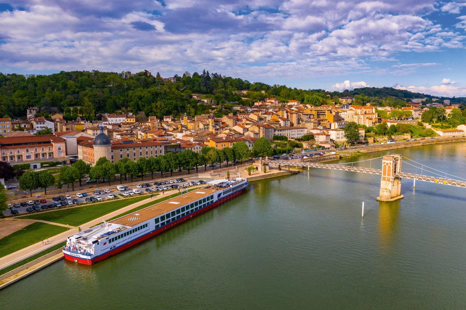 Stadtansicht von Tournon-sur-Rhône, Frankreich, mit Fluss und Hängebrücke.