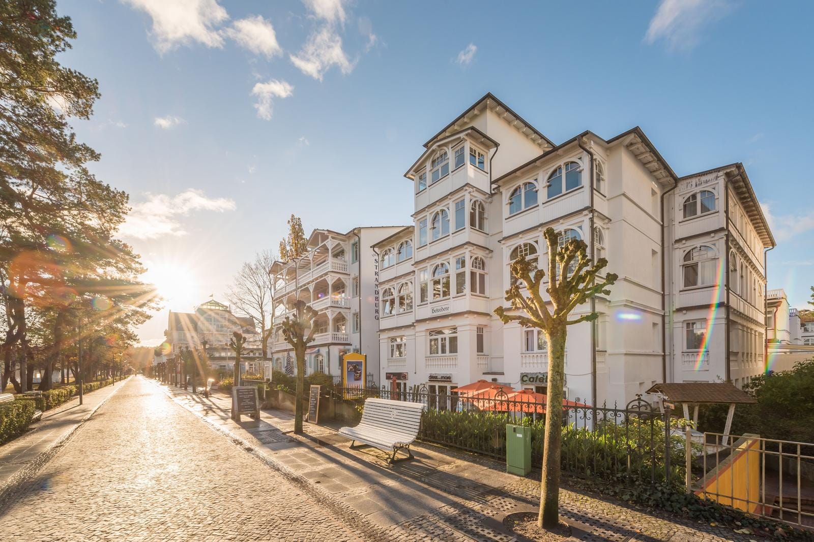 Historische Villa, Bäderarchitektur, weiße Fassade, sonniger Tag, Bäume und Promenade.
