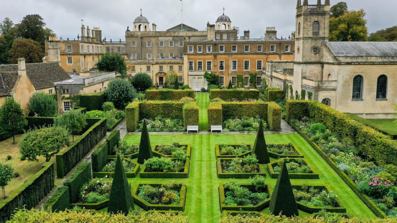 Englischer Landsitz mit symmetrischem Garten, geformten Hecken, altem Gebäude.