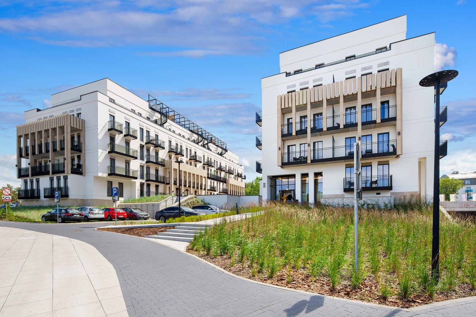 Modernes weißes Hotelgebäude mit Balkonen, umgeben von gepflegten Grünflächen.