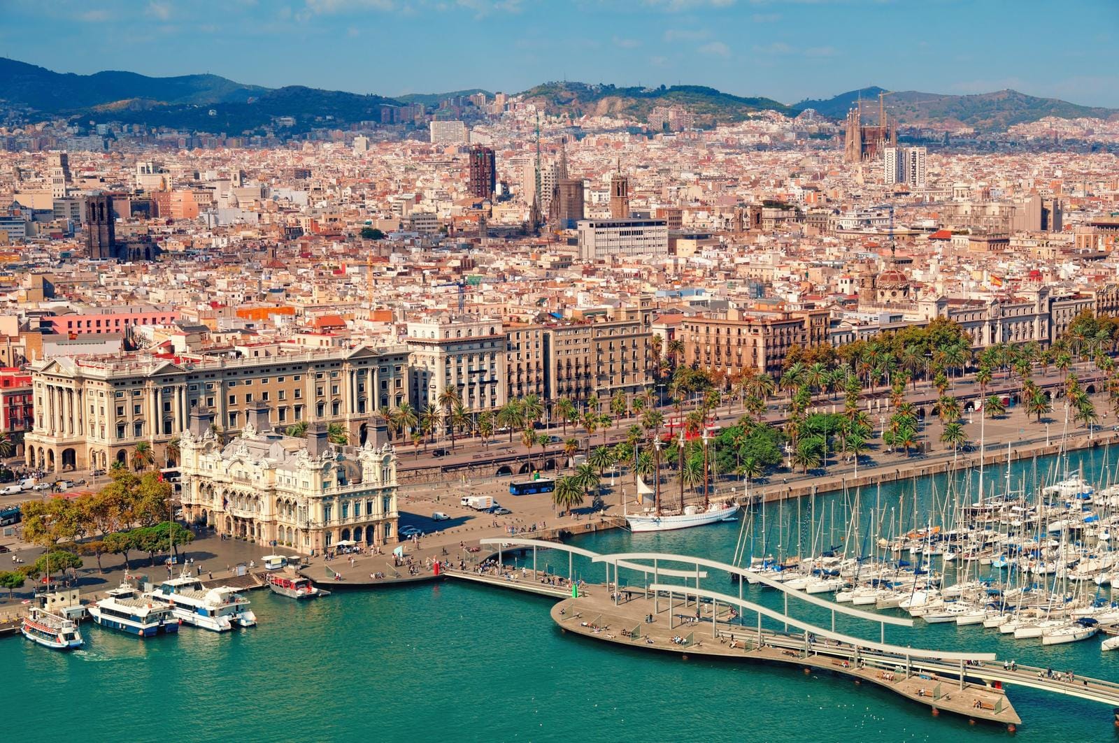 Blick auf Barcelona, Spanien, mit Hafen, Palmenpromenade und dichter urbaner Kulisse.