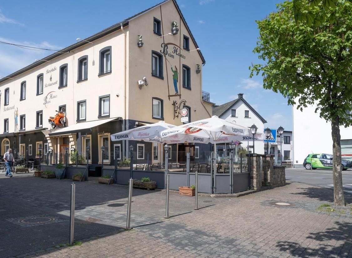 Gelbes Gasthaus mit Terrasse und Sonnenschirmen in einer deutschen Kleinstadt.