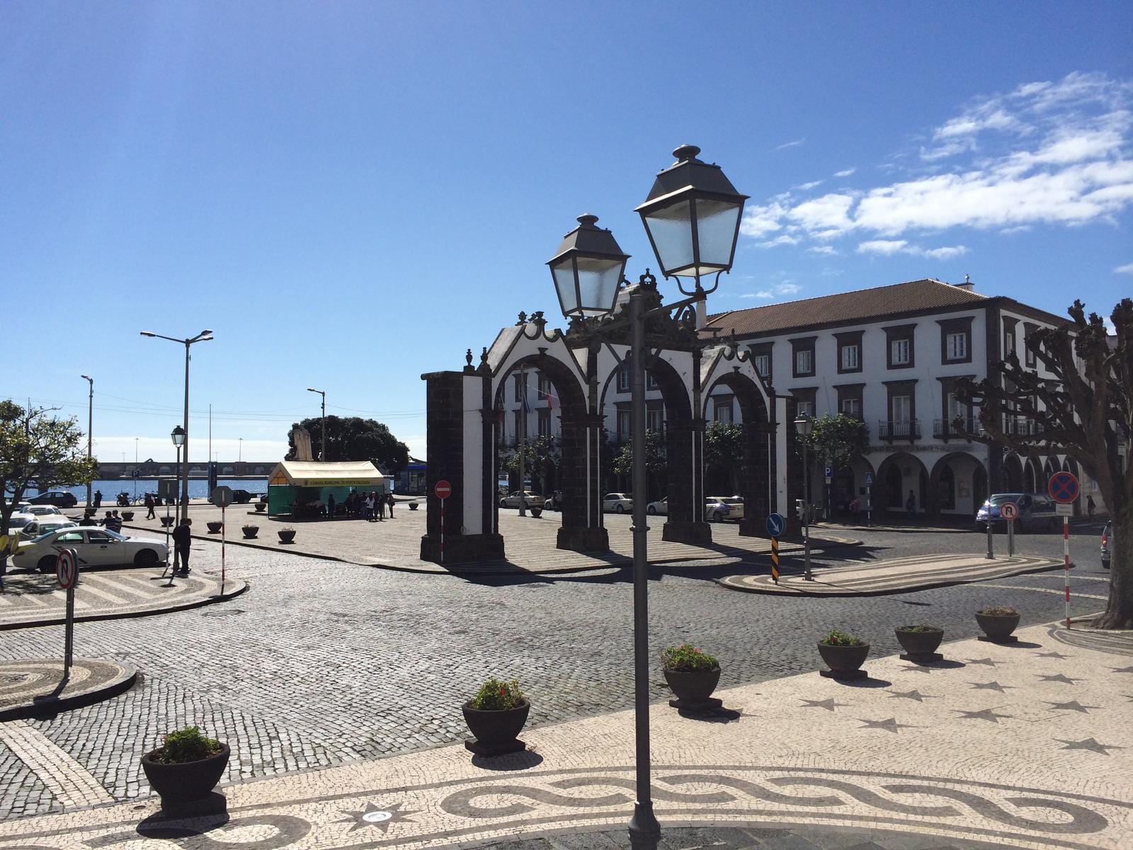 Stadtplatz mit historischem Torbogen, blauer Himmel, gepflasterte Straße, Portugal.