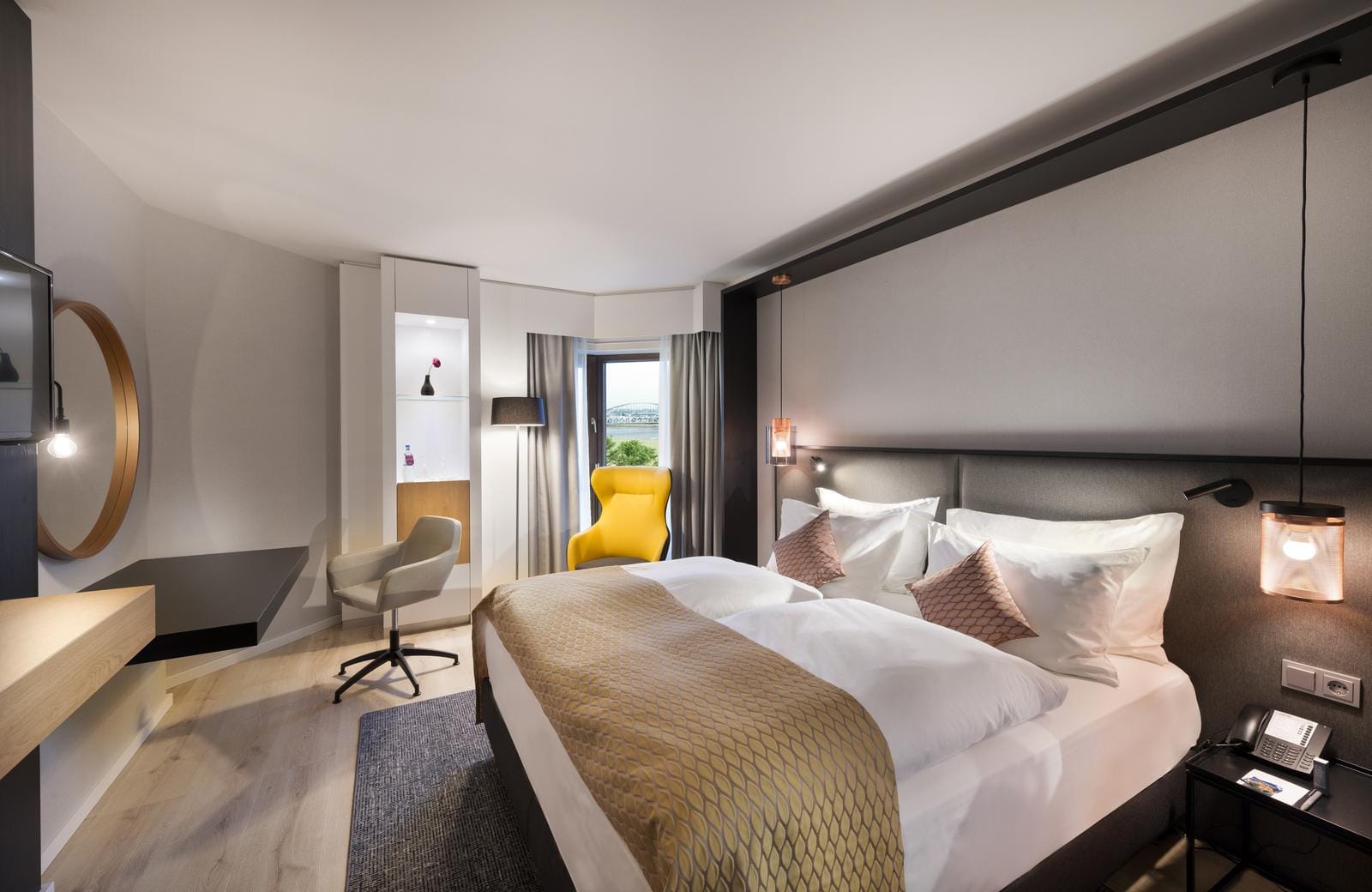 Modernes Hotelzimmer mit Doppelbett, gelbem Sessel und Wanddekoration in neutralen Tönen.