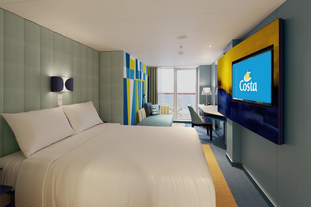 Modernes Hotelzimmer mit Meerblick, hellem Dekor, stilvollem Sofa und großem Fernseher.