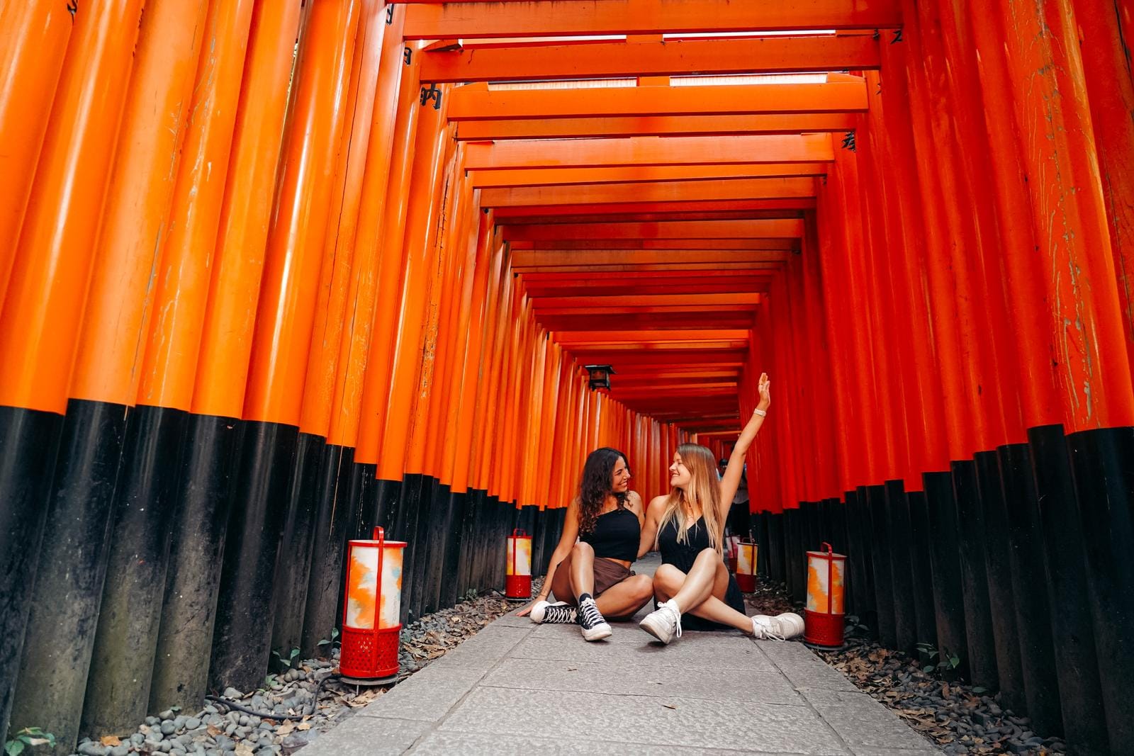 Zwei Personen im roten Torii-Korridor des Fushimi Inari-Taisha, Kyoto, Japan.