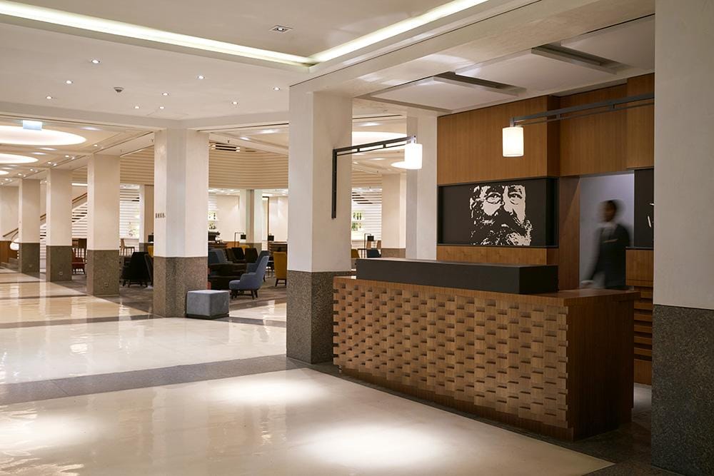 Moderne Hotel-Lobby mit Holzelementen, Kunstwerk und gemütlicher Sitzgelegenheit.