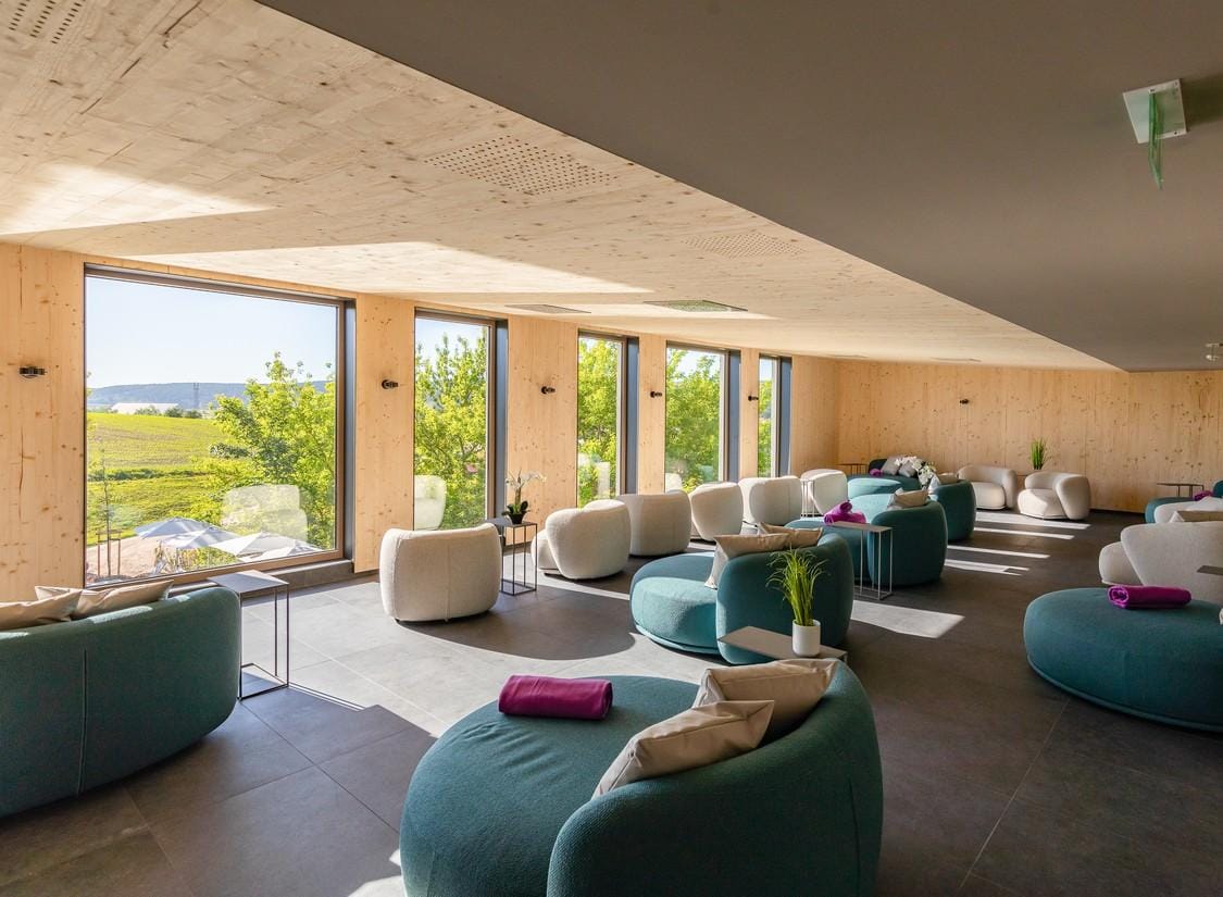 Helle Hotellounge mit modernen, runden Sesseln, großen Fenstern und Blick ins Grüne.