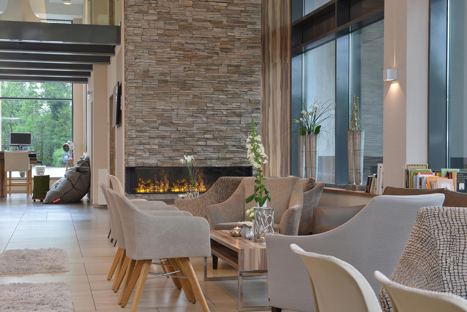 Elegante Hotel-Lobby mit Kamin, modernen Sesseln und großen Fenstern.