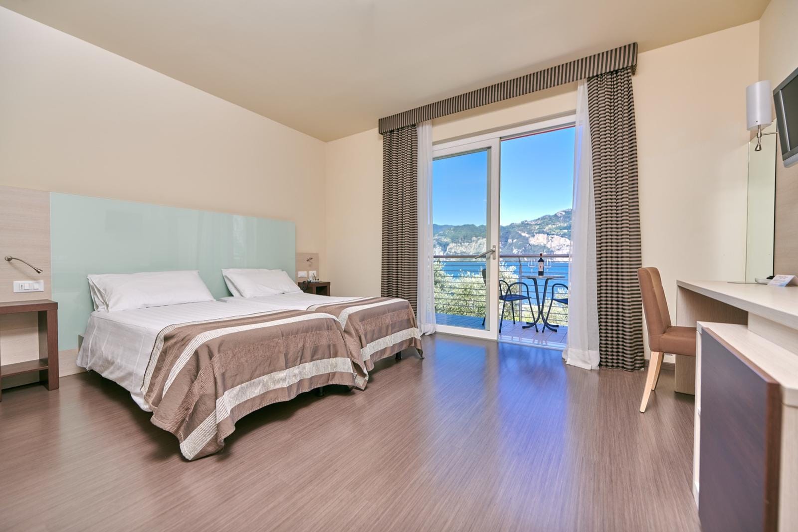 Modernes Hotelzimmer mit Balkon, Meerblick, Twin-Betten, elegantem Interieur.