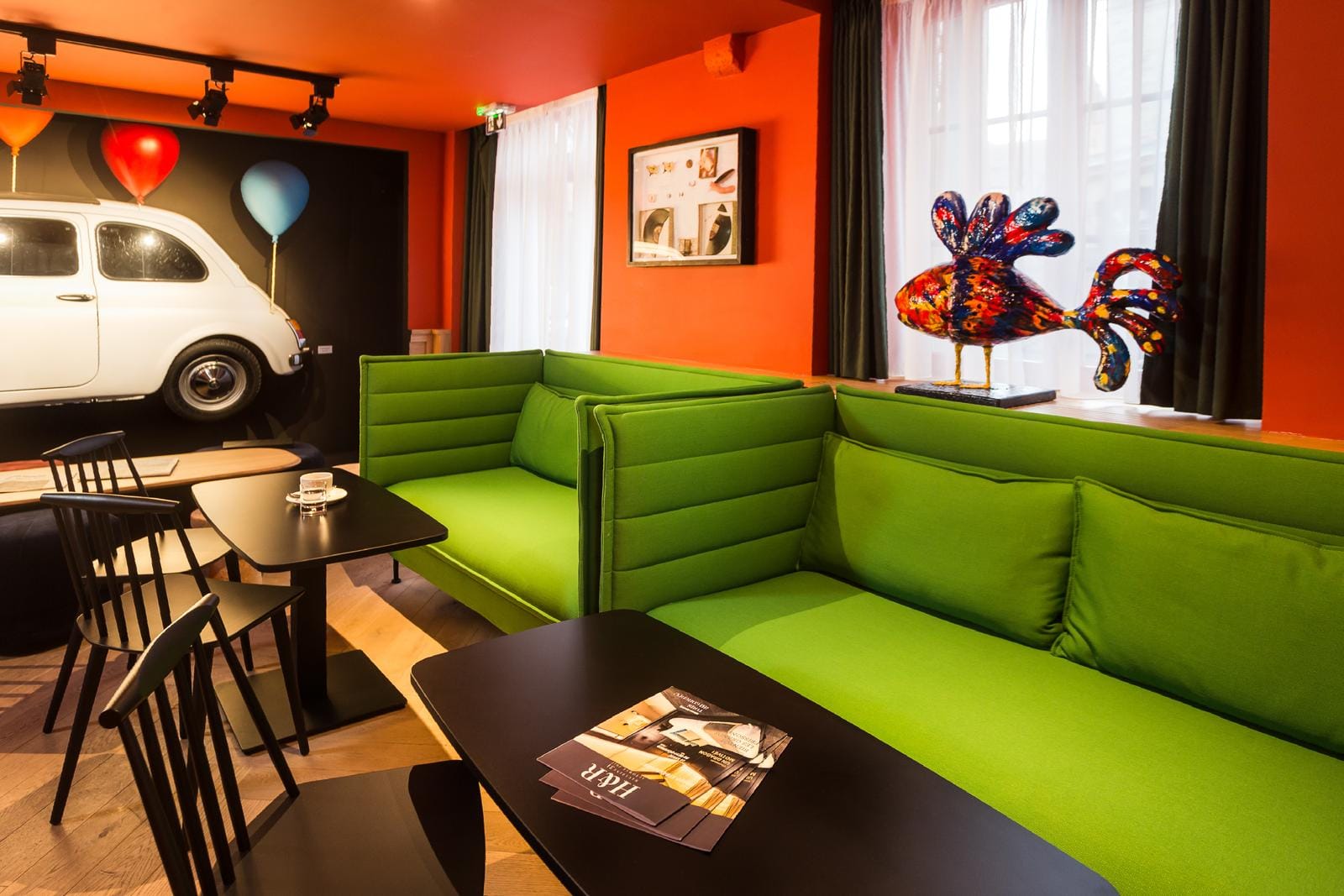 Lebendige Lobby mit grünen Sofas, orangen Wänden und farbenfroher Dekoration.