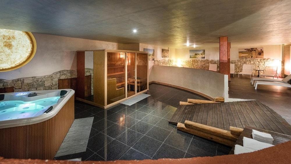 Modernes Hotel-Spa mit Whirlpool, Holzsauna und entspannter Beleuchtung.