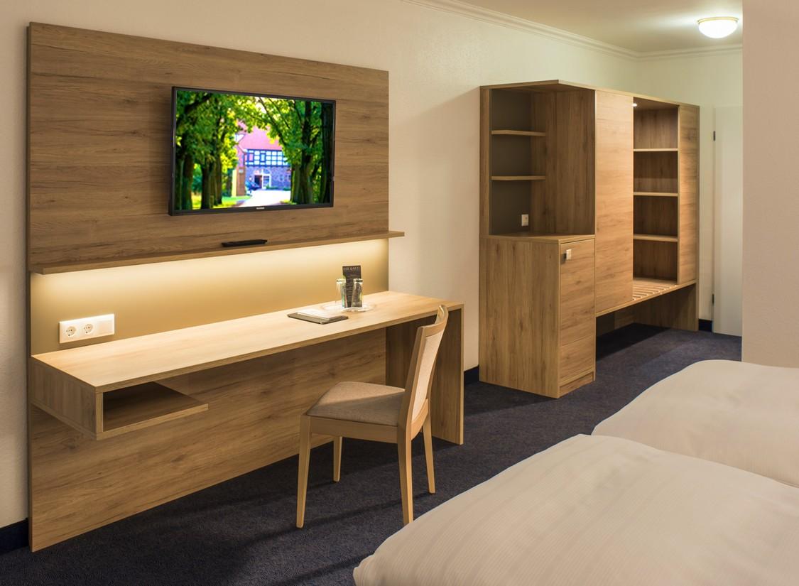 Modernes Hotelzimmer mit Holzdekor, Schreibtisch, Kleiderschrank und Wand-TV.