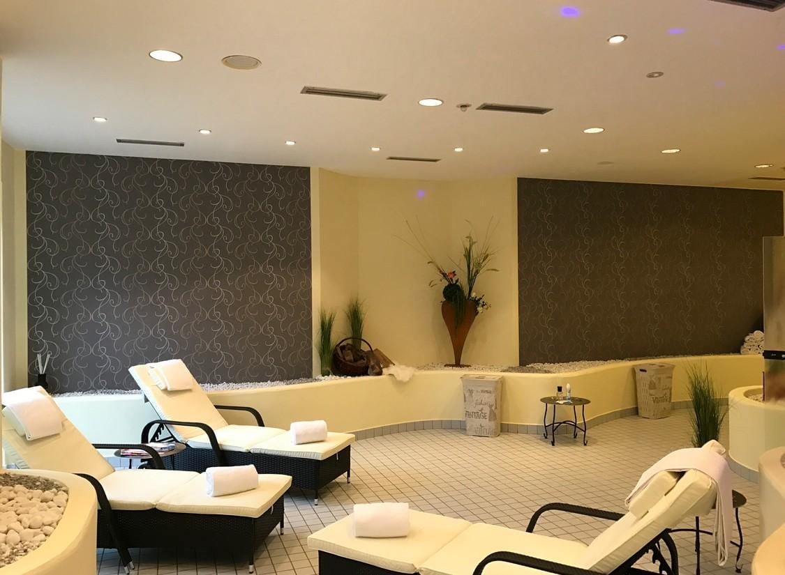 Elegantes Spa mit weißen Liegen, modernen Pflanzenarrangements und stilvollen Wänden.
