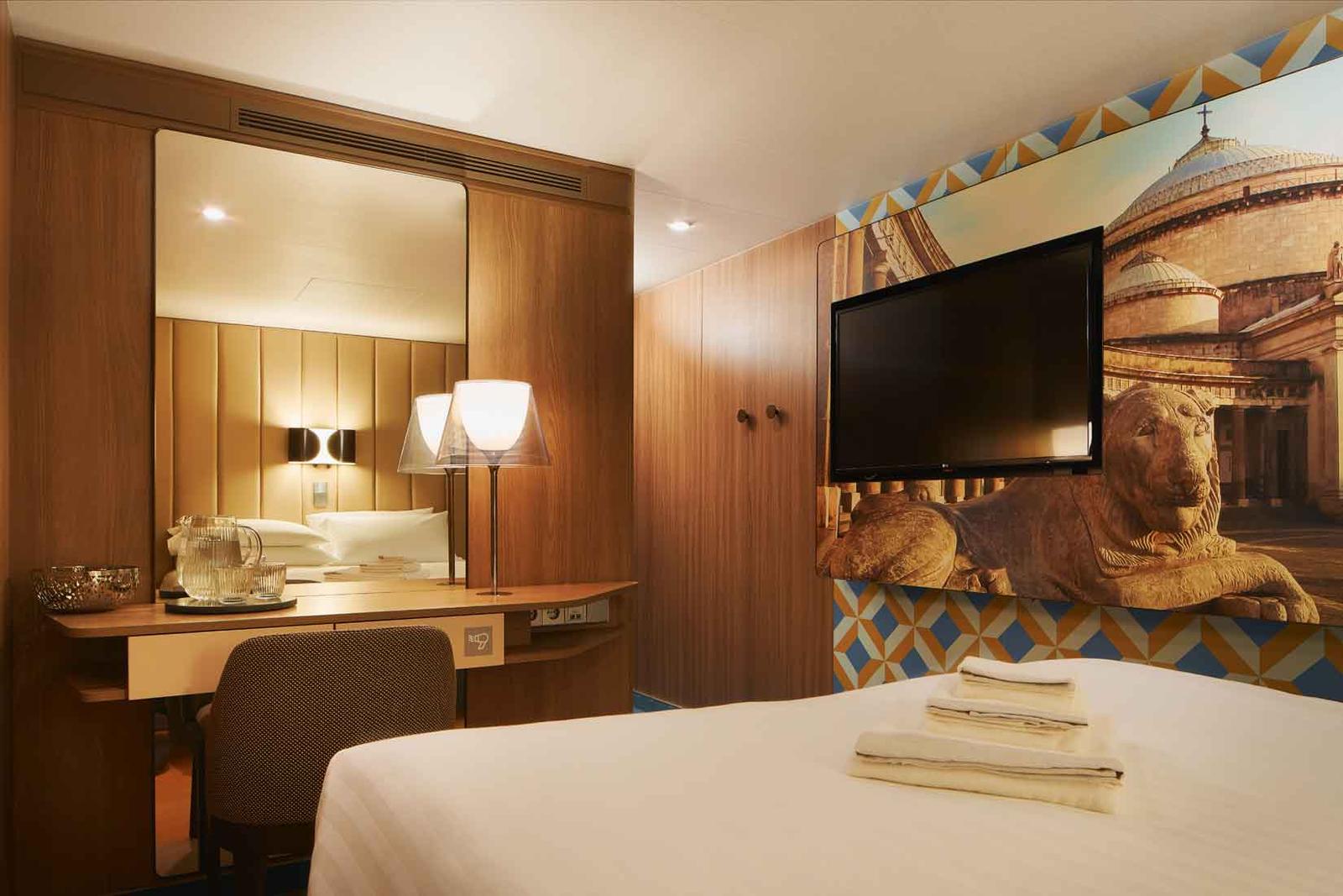 Modernes Hotelzimmer mit Holzverkleidung, großem Wandbild und flauschiger Bettdecke.