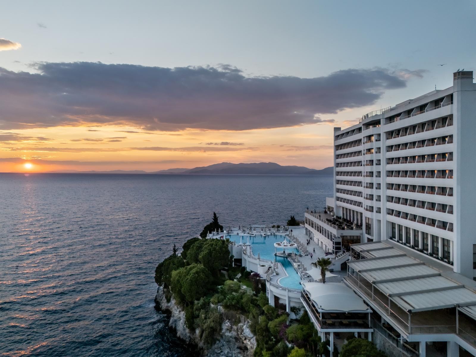 Luxushotel am Meer bei Sonnenuntergang mit Pool und eleganter Architektur.