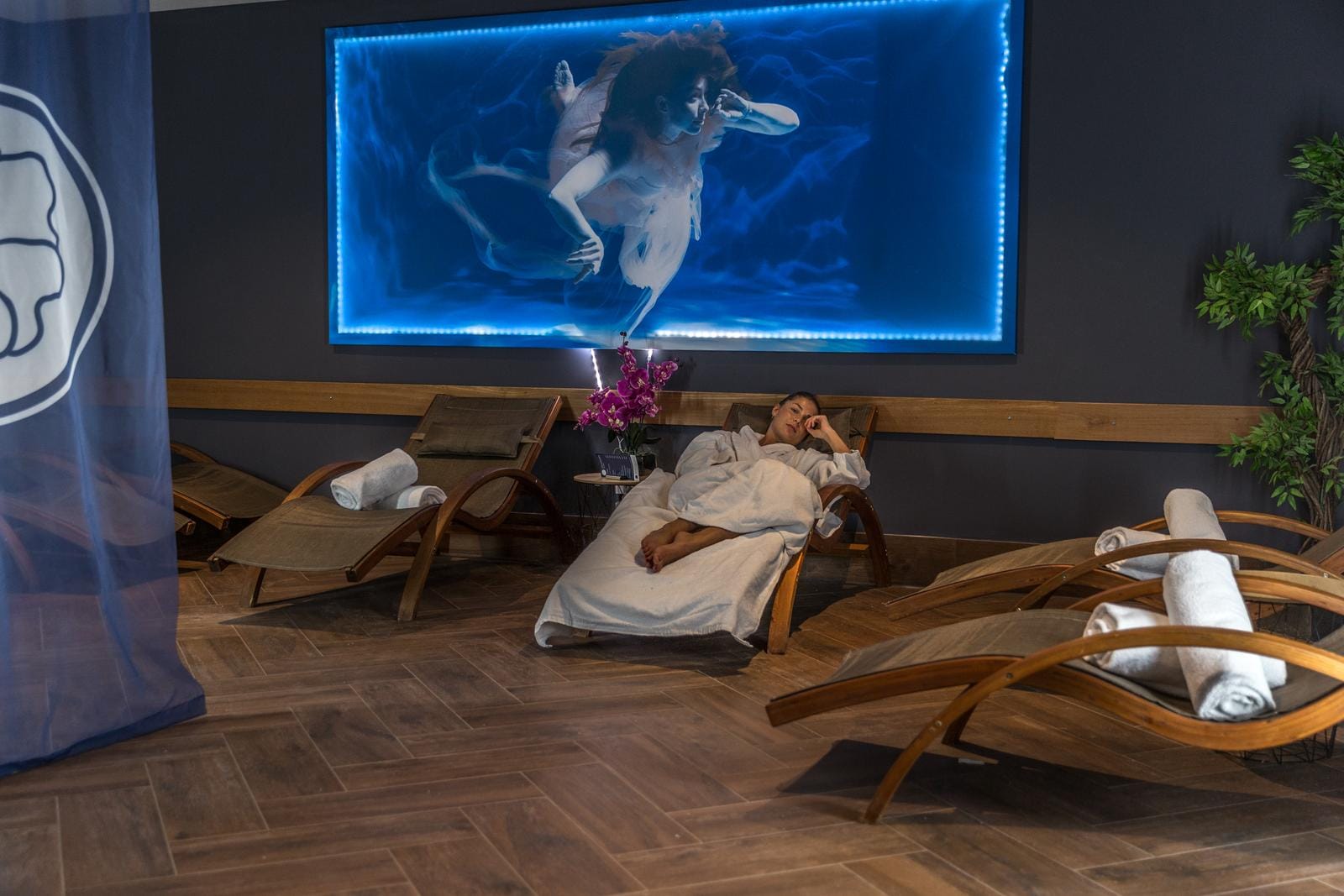 Hotel-Spa mit Holzliegen, Wandbild, entspannte Stimmung und sanfter Beleuchtung.