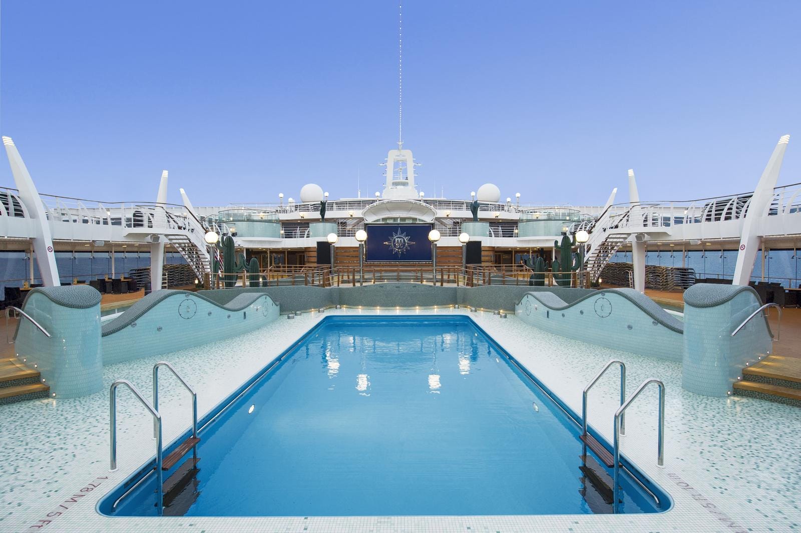 Luxuriöser Kreuzfahrt-Pool an Deck, umgeben von modernen Geländern unter blauem Himmel.