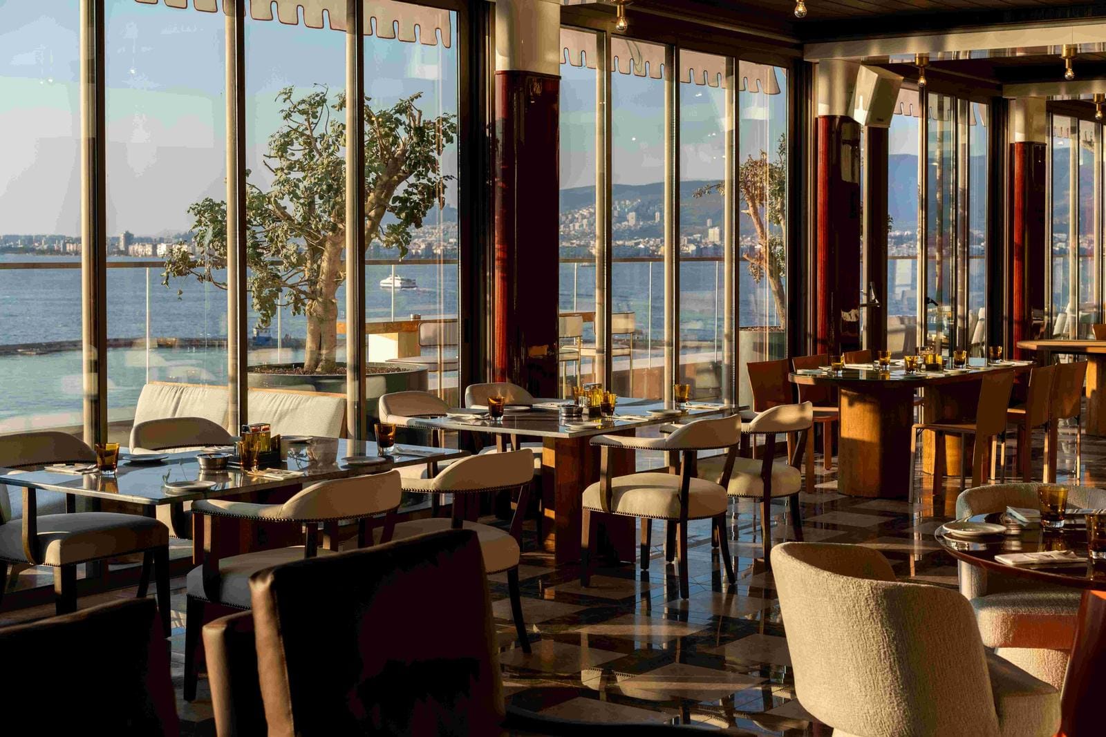 Elegantes Hotelrestaurant mit Meerblick, modernen Möbeln und warmem Licht.