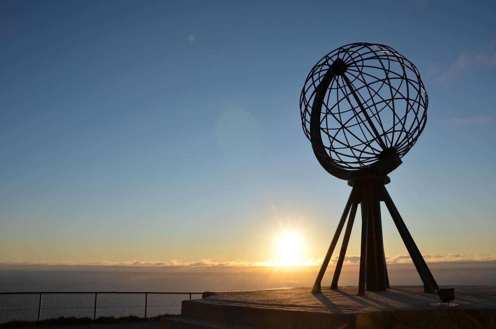 Globus-Denkmal am Nordkap, Norwegen, im Sonnenuntergang vor blauem Himmel.