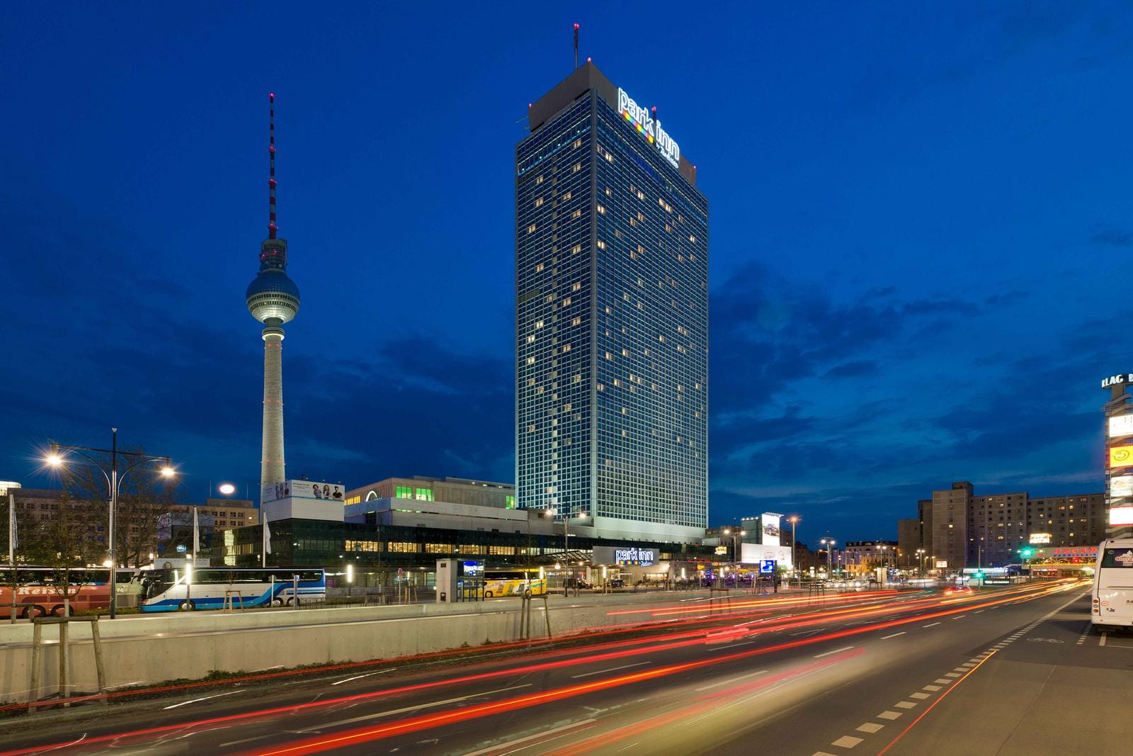 Berlin bei Nacht mit Fernsehturm und beleuchtetem Hotel.